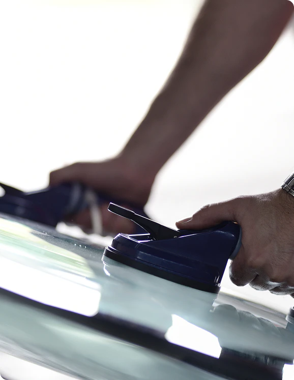 Auto glass technician holding windshield using suction cups